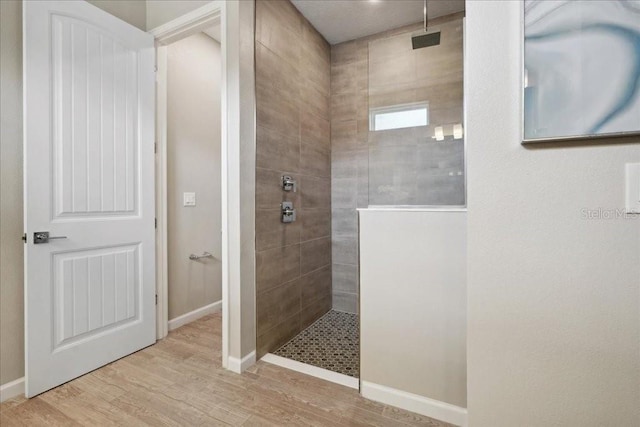 bathroom with hardwood / wood-style floors and a tile shower