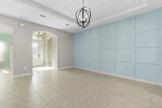 empty room with a notable chandelier, light tile patterned floors, french doors, and a tray ceiling