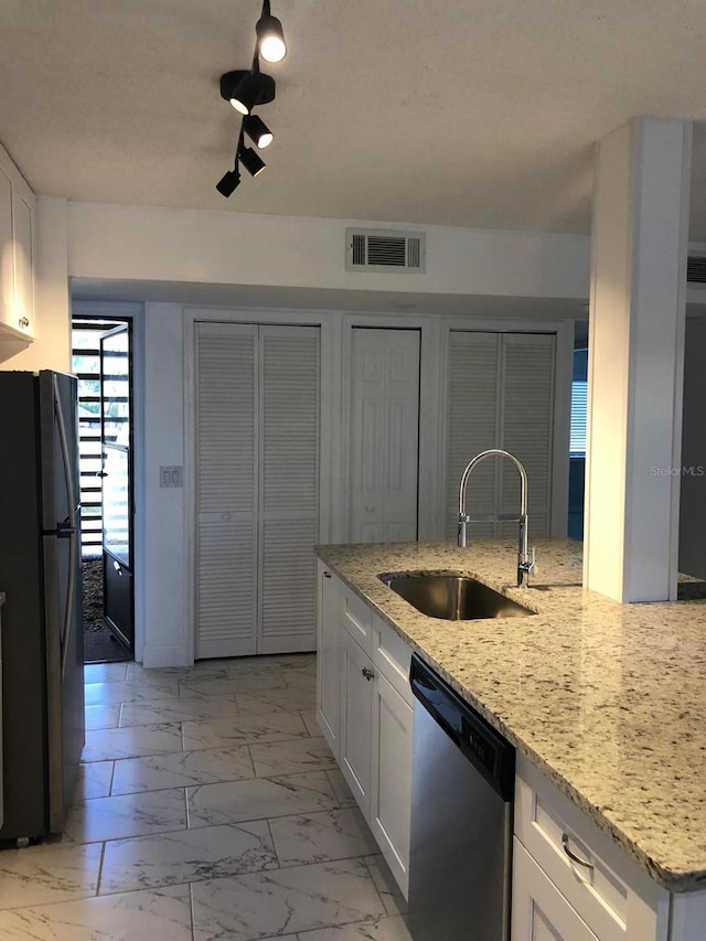 kitchen featuring black refrigerator, dishwasher, sink, white cabinets, and light stone countertops