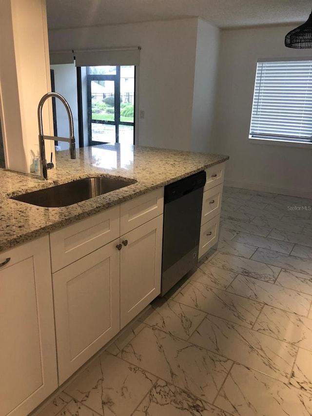 kitchen featuring light stone counters, sink, white cabinets, and dishwasher