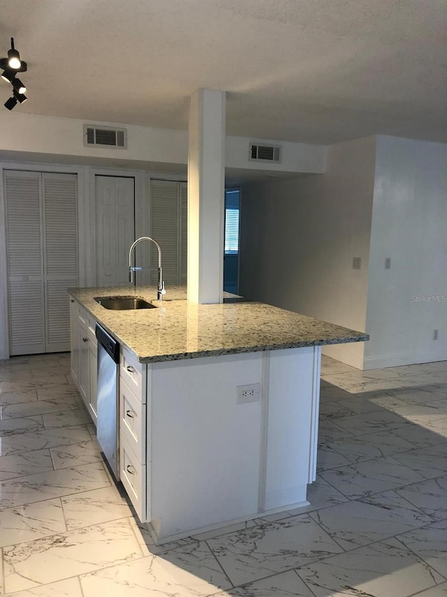 kitchen with white cabinetry, sink, light stone counters, stainless steel dishwasher, and a kitchen island with sink