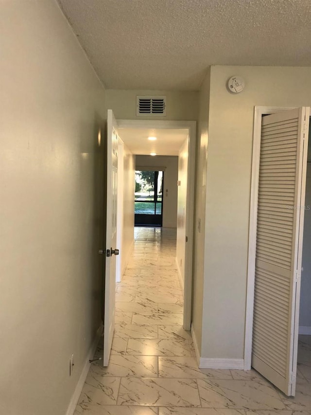 hall featuring a textured ceiling