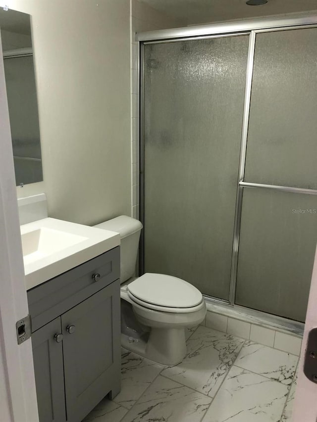 bathroom featuring an enclosed shower, vanity, and toilet