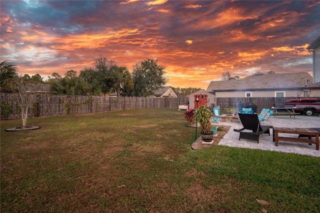 yard at dusk featuring a patio and a storage unit