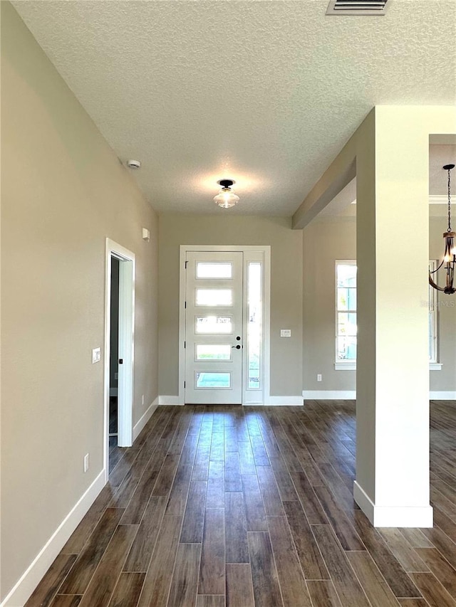 foyer featuring dark hardwood / wood-style flooring, a textured ceiling, and a notable chandelier