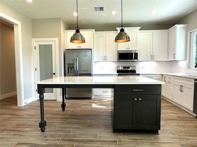 kitchen with pendant lighting, a center island, white cabinets, and appliances with stainless steel finishes