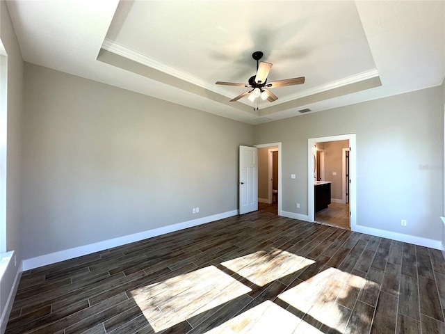 empty room with dark hardwood / wood-style floors, ceiling fan, crown molding, and a tray ceiling