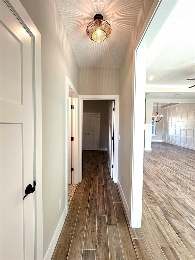 hallway featuring wood-type flooring and an inviting chandelier