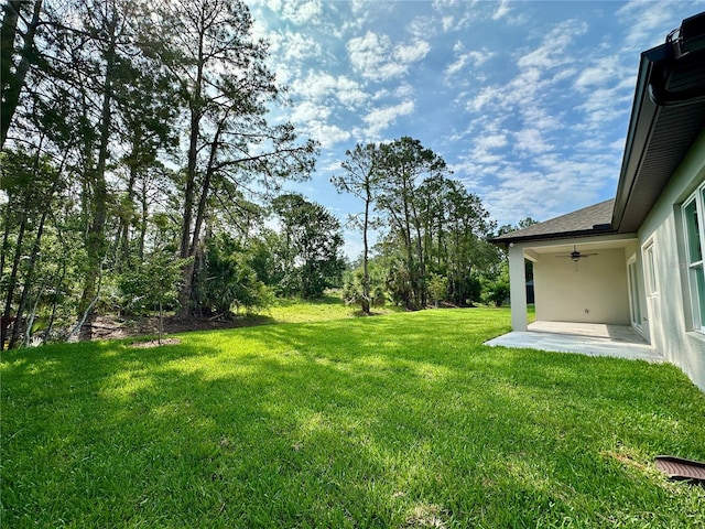 view of green lawn with ceiling fan and a patio