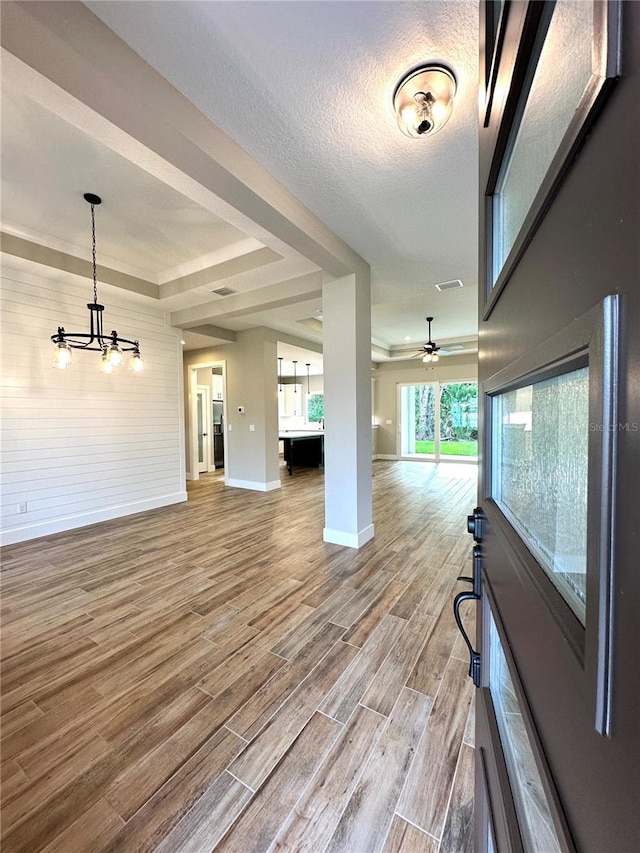 6 Lake Pl, Palm Coast, FL 32137 - unfurnished living room with baseboards, wood finished floors, a chandelier, a tray ceiling, and ceiling fan
