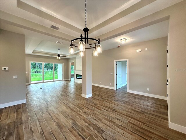 6 Lake Pl, Palm Coast, FL 32137 - unfurnished living room with a tray ceiling, baseboards, dark wood-style flooring, a chandelier, and a ceiling fan