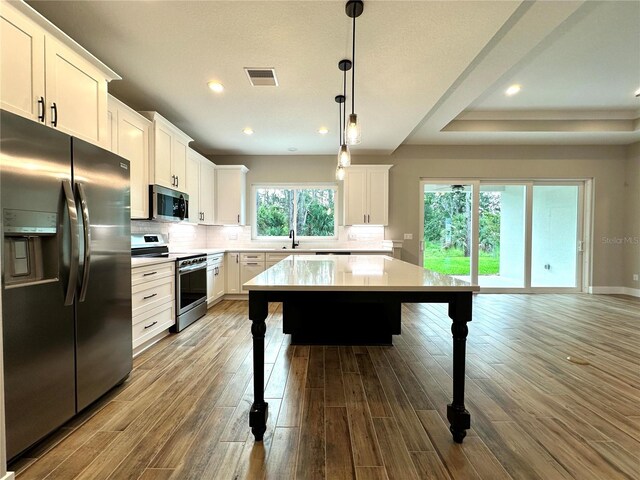 6 Lake Pl, Palm Coast, FL 32137 - kitchen with stainless steel appliances, dark wood-style floors, decorative backsplash, light countertops, and a breakfast bar area