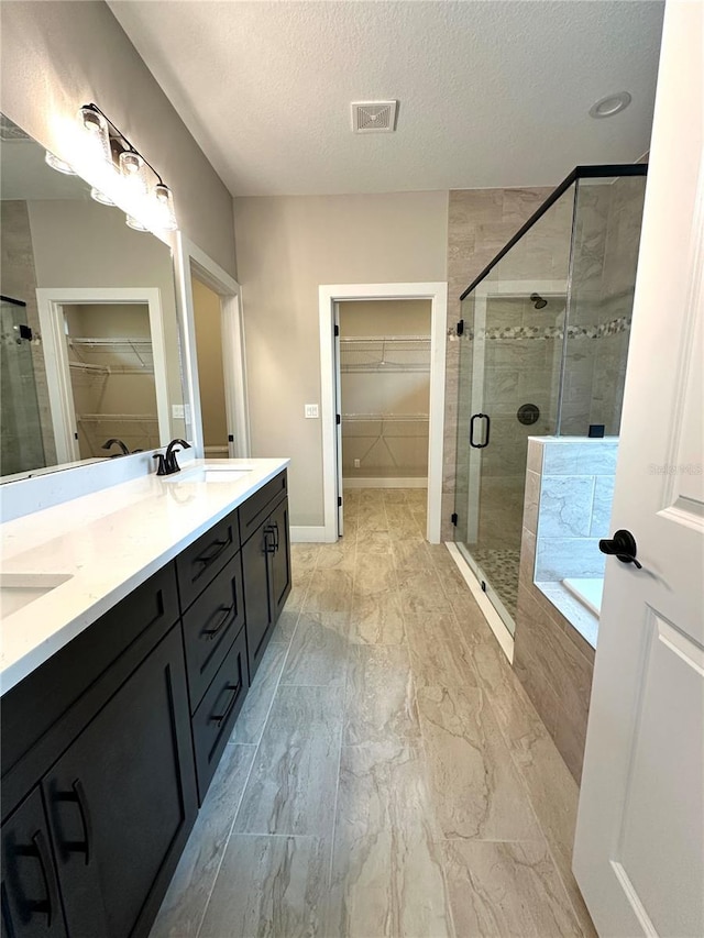 6 Lake Pl, Palm Coast, FL 32137 - full bathroom with double vanity, a shower stall, a garden tub, a spacious closet, and a textured ceiling