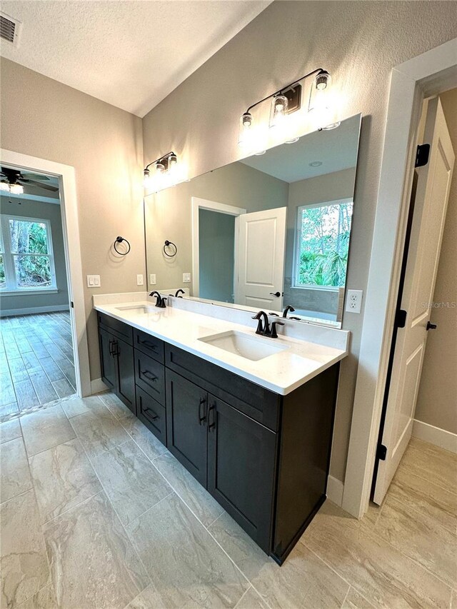 6 Lake Pl, Palm Coast, FL 32137 - bathroom with baseboards, double vanity, plenty of natural light, a textured ceiling, and a ceiling fan