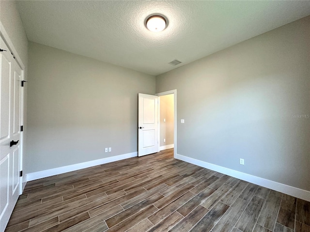 6 Lake Pl, Palm Coast, FL 32137 - unfurnished bedroom with dark wood-type flooring, baseboards, and a textured ceiling