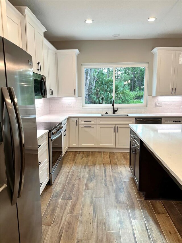 6 Lake Pl, Palm Coast, FL 32137 - kitchen featuring stainless steel appliances, a sink, white cabinets, light countertops, and backsplash