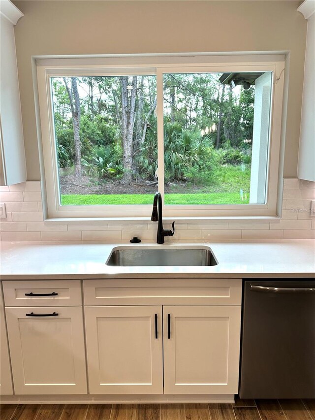 6 Lake Pl, Palm Coast, FL 32137 - kitchen featuring stainless steel dishwasher, a sink, light countertops, white cabinets, and backsplash