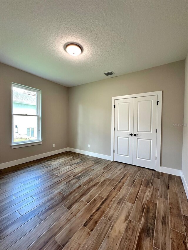 6 Lake Pl, Palm Coast, FL 32137 - unfurnished bedroom featuring wood finished floors, a textured ceiling, baseboards, and a closet