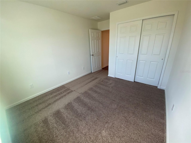 unfurnished bedroom with dark colored carpet and a closet