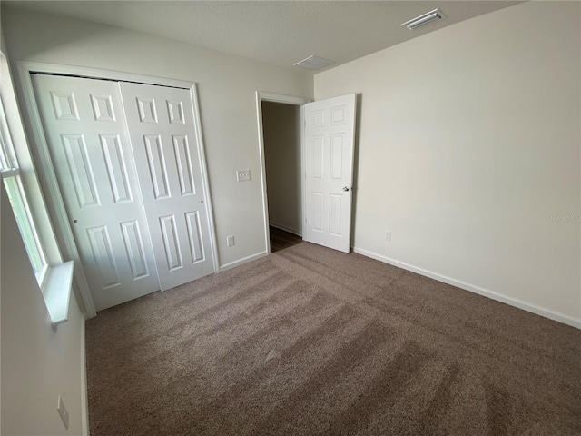 unfurnished bedroom featuring dark carpet and a closet