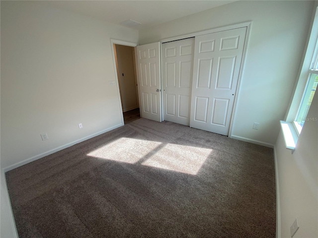 unfurnished bedroom featuring a closet and dark carpet