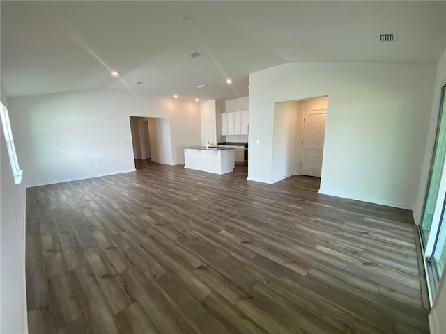 unfurnished living room featuring dark wood-type flooring and vaulted ceiling