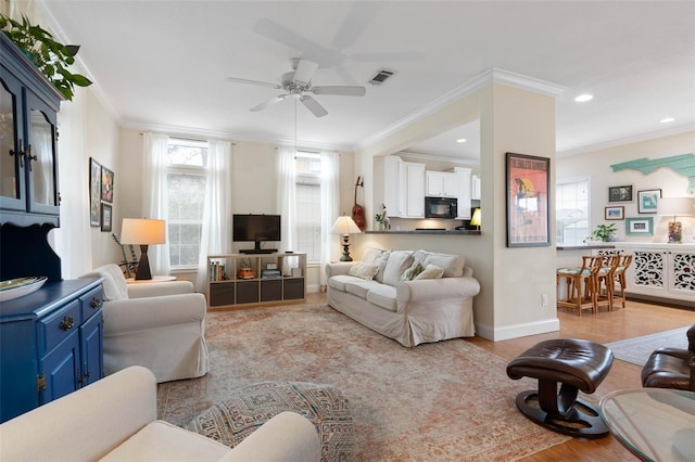 living room with light hardwood / wood-style floors, ceiling fan, and ornamental molding