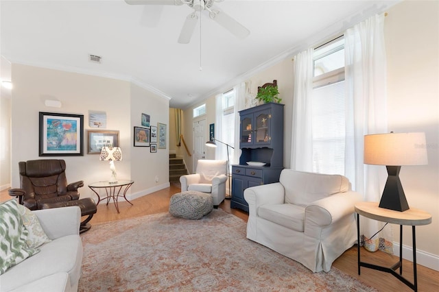 living room with light hardwood / wood-style floors, ceiling fan, and ornamental molding