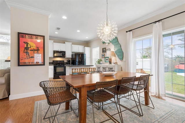 dining room with crown molding, light wood-type flooring, and an inviting chandelier