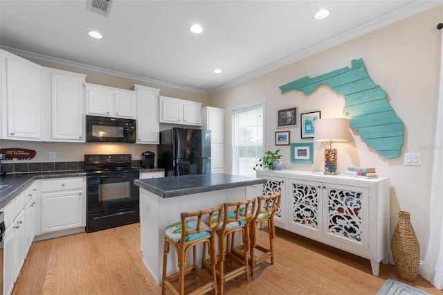 kitchen with a center island, black appliances, crown molding, light wood-type flooring, and white cabinetry