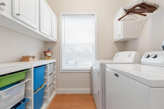 laundry area with cabinets, washer and dryer, and light wood-type flooring