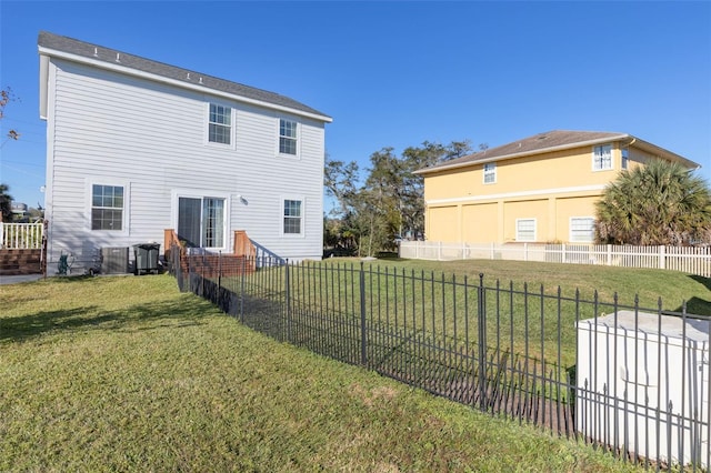 rear view of house featuring central AC unit and a yard