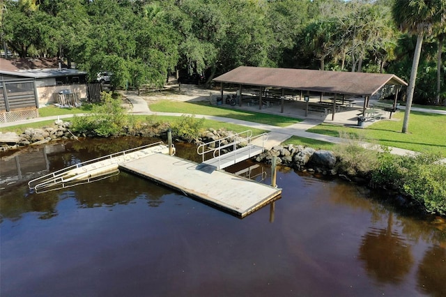 view of dock with a lawn and a water view