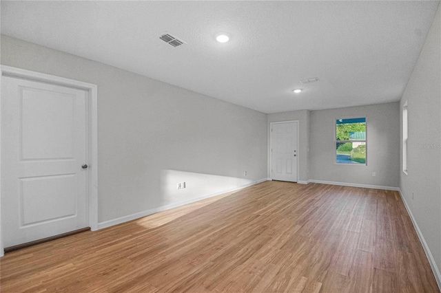 spare room featuring a textured ceiling and light hardwood / wood-style flooring