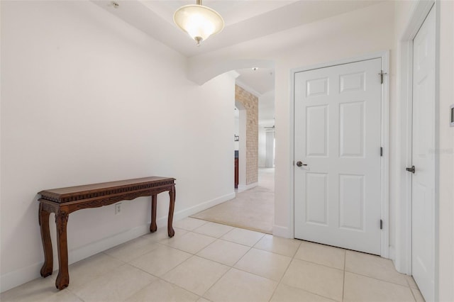 hall featuring light tile patterned floors and ornamental molding