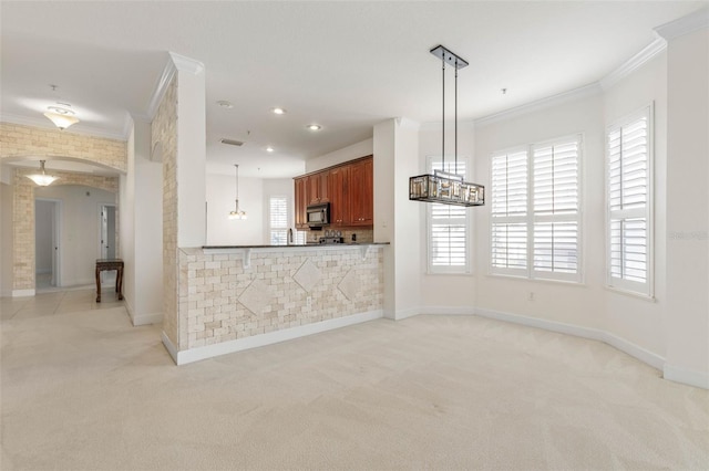 kitchen with decorative light fixtures, light colored carpet, ornamental molding, and kitchen peninsula