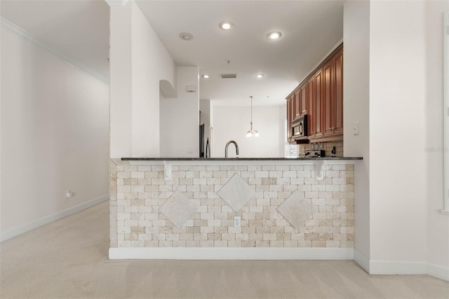 kitchen featuring kitchen peninsula, a breakfast bar, crown molding, sink, and pendant lighting