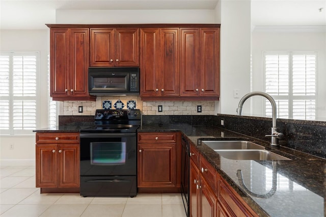 kitchen featuring a wealth of natural light, dark stone counters, sink, black appliances, and light tile patterned floors