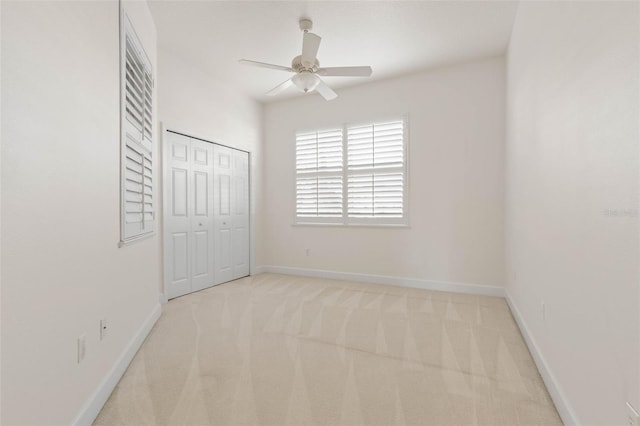 unfurnished bedroom with ceiling fan, light carpet, and a closet