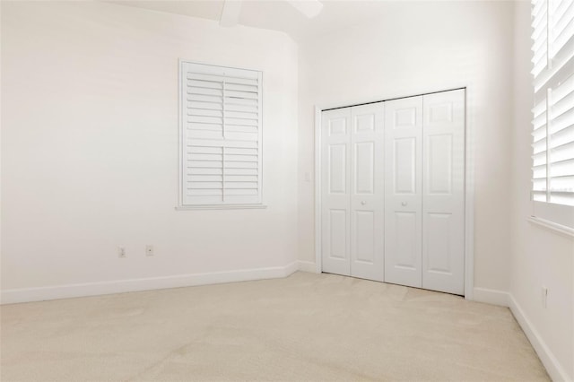 unfurnished bedroom featuring ceiling fan, light colored carpet, and a closet