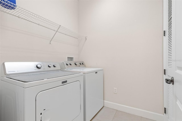 clothes washing area featuring light tile patterned flooring and washing machine and clothes dryer