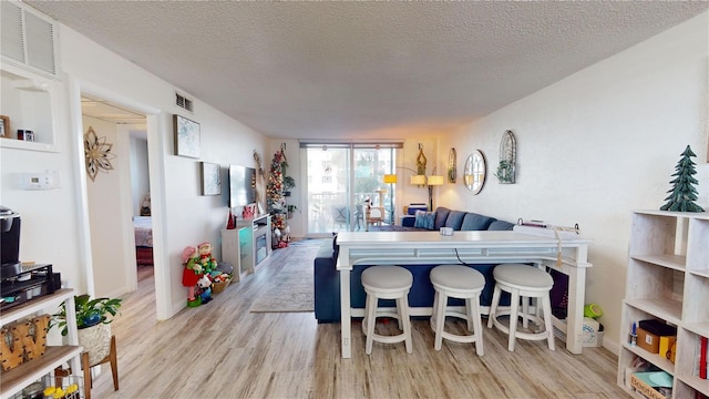 interior space with a kitchen breakfast bar, light hardwood / wood-style floors, a textured ceiling, and a wall of windows