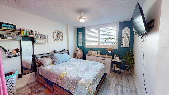 bedroom with a textured ceiling, light wood-type flooring, and ceiling fan