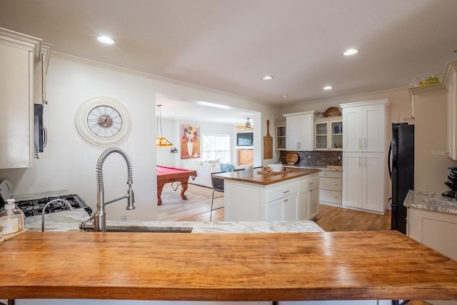 kitchen with a center island, black fridge, crown molding, white cabinets, and pool table