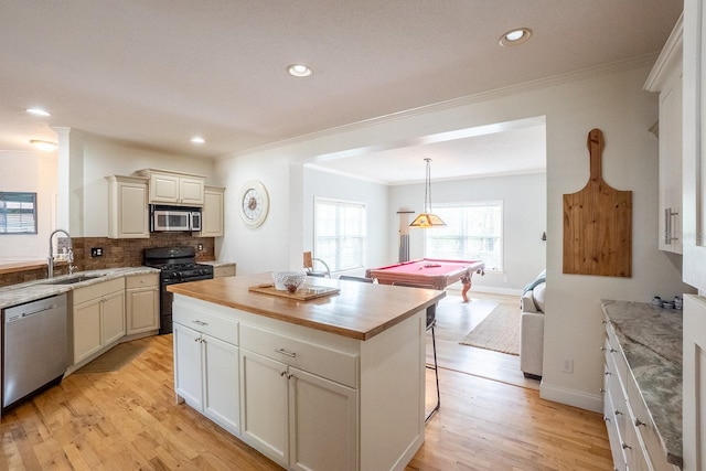 kitchen featuring appliances with stainless steel finishes, sink, pendant lighting, a center island, and pool table