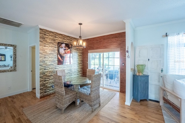 dining space with crown molding, a notable chandelier, and light wood-type flooring