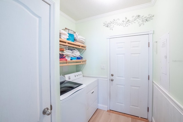 clothes washing area featuring washing machine and dryer, light hardwood / wood-style flooring, and crown molding