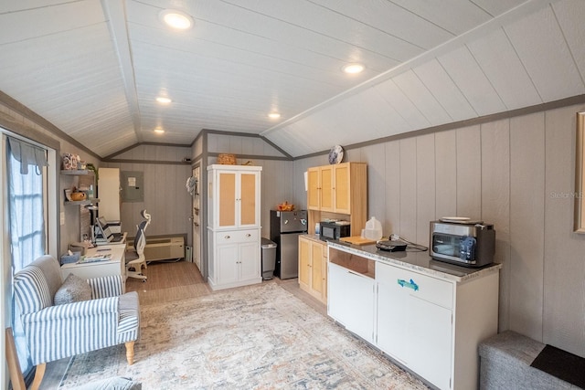 kitchen with white cabinetry, electric panel, stainless steel fridge, wood walls, and lofted ceiling