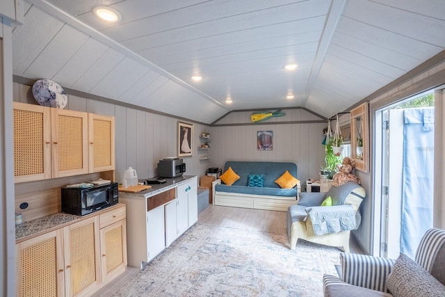 kitchen with light wood-type flooring, white cabinetry, vaulted ceiling, and wooden walls