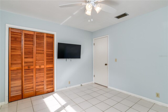 unfurnished bedroom featuring ceiling fan, a closet, and light tile patterned floors